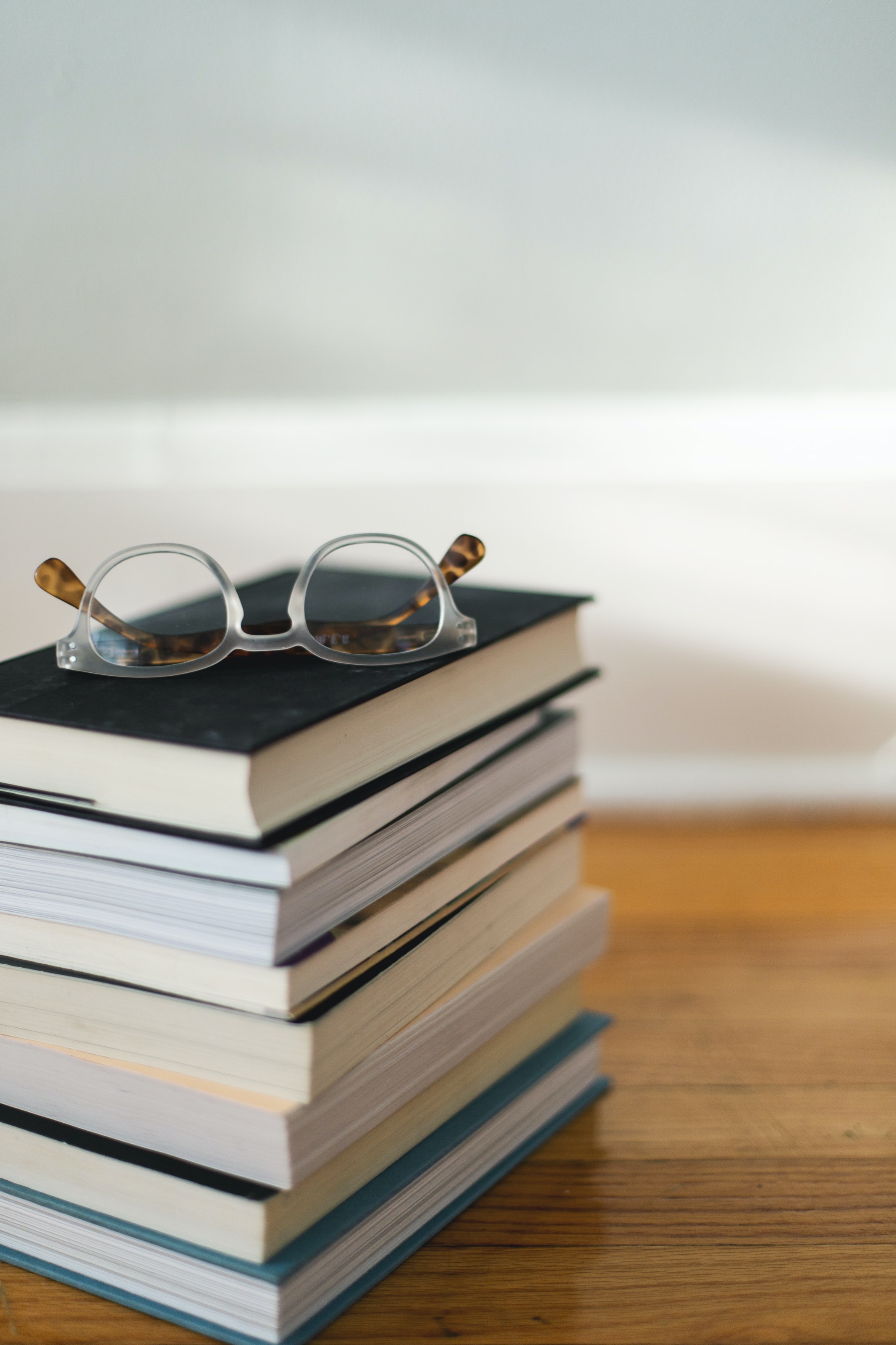 A stack of books with a pair of glasses.